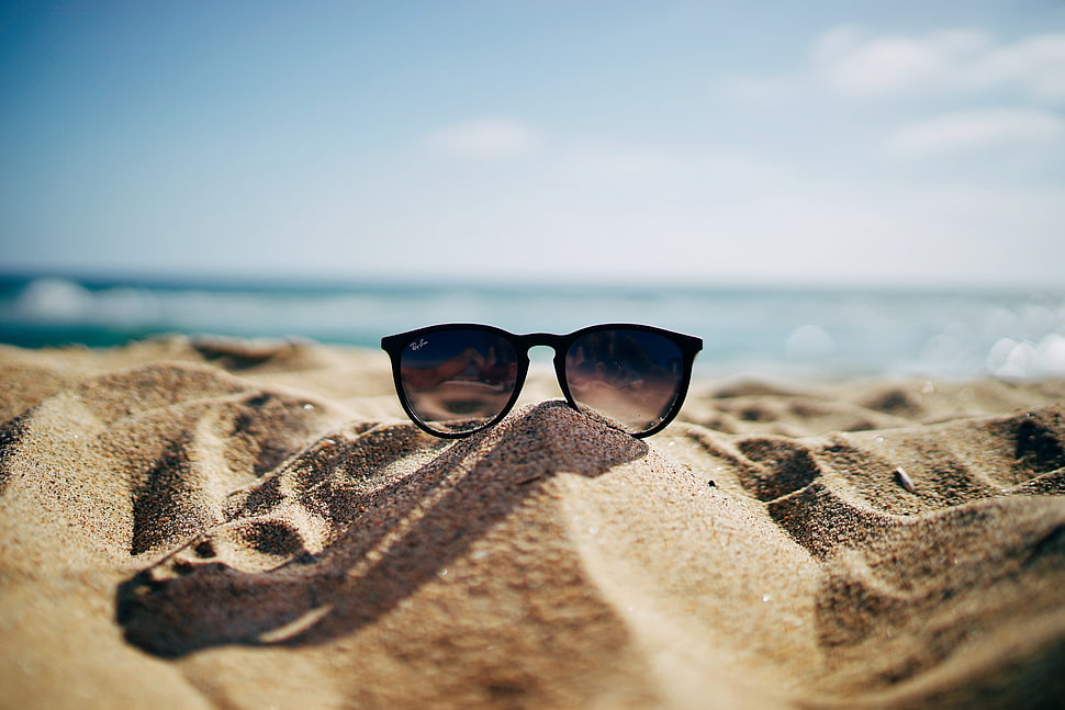 photo of a brown framed Ray-Ban wayfarer sunglasses on brown sands HD wallpaper