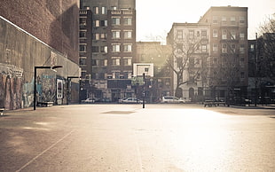 outdoor basketball court beside concrete wall and storey buildings under white sky