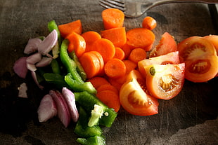 sliced onions, tomatoes, carrots, green bell peppers on chopping board