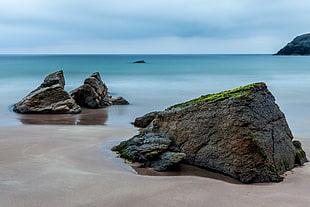 gray stone form near sea under blue sky HD wallpaper