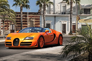 photo of orange super car near white concrete building HD wallpaper