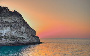 brown cliff near ocean at golden hour