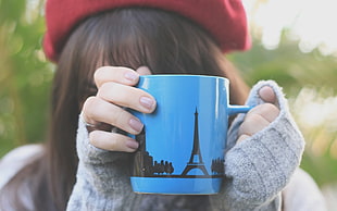 woman holding blue and black ceramic mug in close-up photography