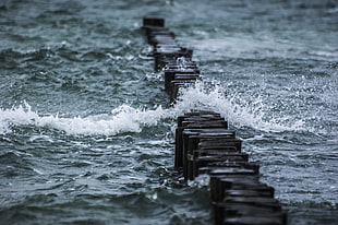 waves crushing on pile of black rocks