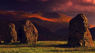 three Stonehenges near mountain cliff HD wallpaper