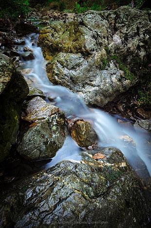 time lapse photography of river between rocky surface