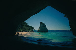 silhouette of people walking on beach near cave HD wallpaper