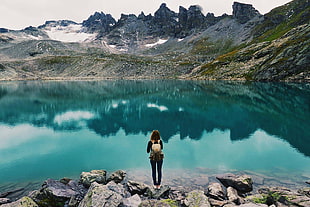 woman standing on rock near body of water