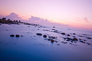 blue sea and brown rock formations under white cloudy sky photo