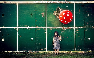 child holding red and white balloon