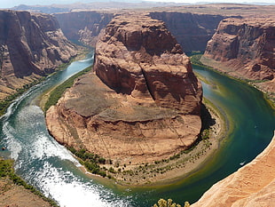 aerial photo of brown rock formation between green body of water