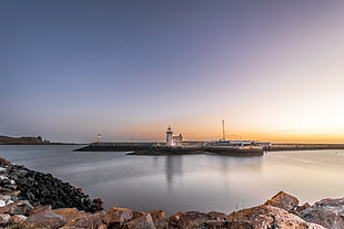 white concrete lighthouse beside body of water during sunlight HD wallpaper