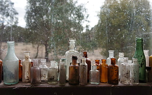 assorted glass bottle beside window HD wallpaper