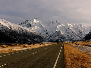 gray concrete road surround by black and white rocky mountain with snow, sefton