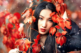 woman in black long-sleeved shirt covered by red plants close-up photo