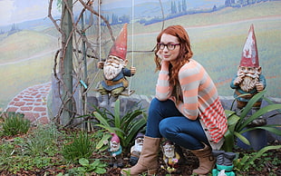 woman in brown and orange striped jacket sitting near gnome decors HD wallpaper