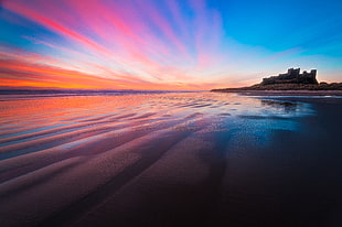 body of calm water at sunset