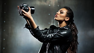 woman in black leather top taking photo of self using SLR camera HD wallpaper