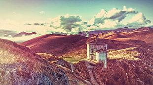 white concrete building in middle of mountain under sunset