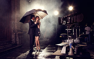 man in black suit holding black umbrella beside woman in black mini dress wearing black heels HD wallpaper