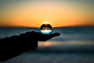 crystal ball on person's hand during yellow sunset HD wallpaper