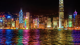 photo of city light near sea during night time HD wallpaper