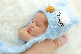baby with blue and white critter cap on white textile HD wallpaper