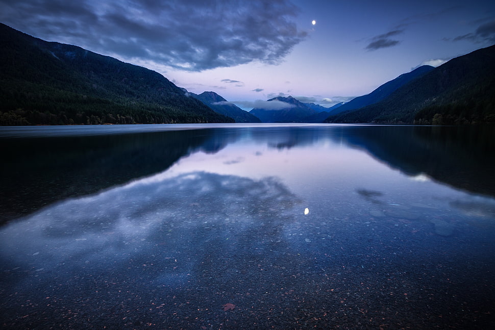 body of water between green mountains under gray cloudy sky HD wallpaper