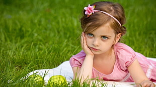 girl's laying on green grass field