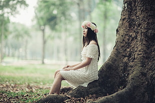 sitting woman wearing floral boho headband and white tiered off-shoulder dress behind tall tree HD wallpaper