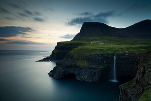 mountain with waterfalls beside ocean