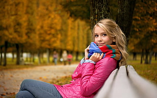 woman in pink bubble jacket sitting on bench
