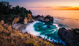 aerial photo of ocean with rocks during sunset