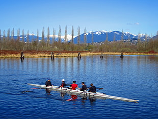 five person on boat floating on rippling body of water over looking mountain and trees HD wallpaper