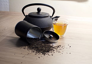 coffee pot and beans beside glass on table