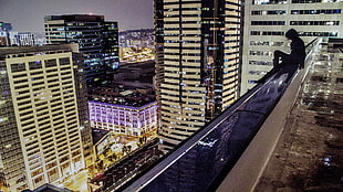 person sitting on a rooftop during night time