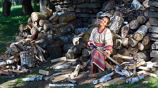 woman in white, red and brown traditional dress sitting on firewood lot HD wallpaper