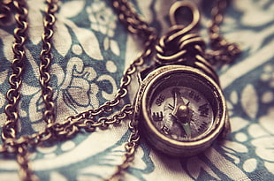 photo of silver-colored compass on white and green floral textile