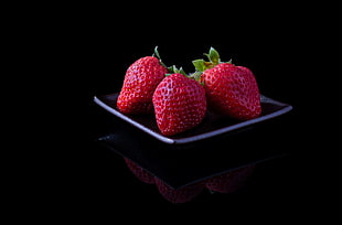 three strawberries with black plate