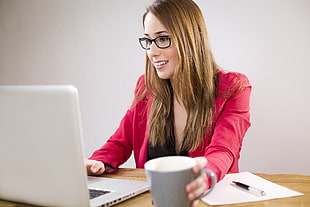 woman holding a coffee mug on office table while working use a silver MacBook in white wall paint room HD wallpaper