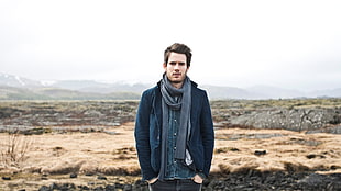 man wearing blue blazer and jeans with gray scarf