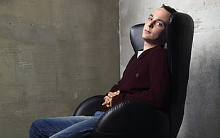 man in brown long sleeve shirt and blue jeans sitting on black leather chair HD wallpaper