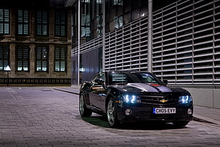 black and grey Chevrolet Camaro on gray top road beside building