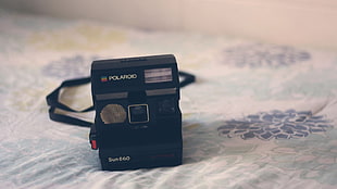 selective focus photography of Polaroid instant camera on bed comforter HD wallpaper