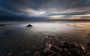 body of water under cloudy sky during sunrise