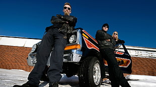 photography of three man all in black suit leaning on black sports car