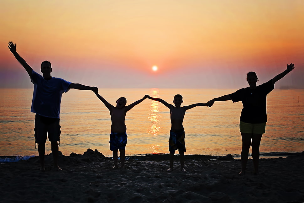 silhouette of man, woman with their two boys holding while raising their hands in front of beach during sunset HD wallpaper