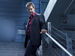 men's black suit jacket holding gray handrails HD wallpaper
