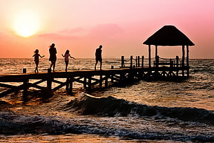 silhouette of family walking on dock beside waving sea HD wallpaper