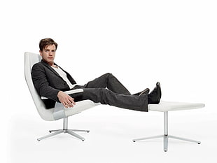 man wearing black formal suit sitting on glider chair HD wallpaper